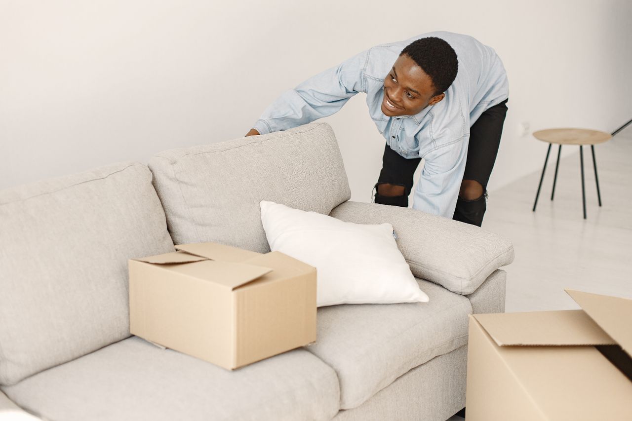 Jeune homme souriant en train d’organiser des cartons dans un salon moderne.