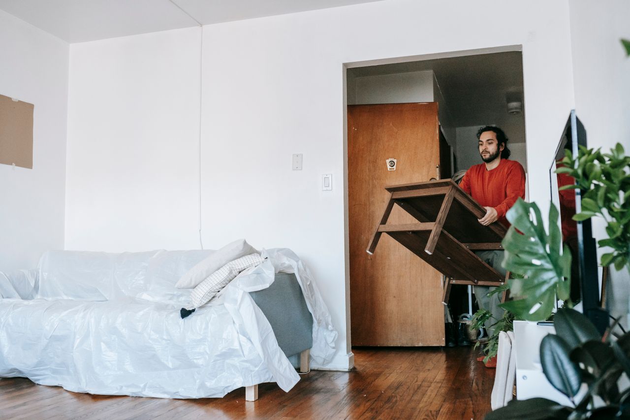 Un homme portant une table en bois pendant un déménagement dans un appartement contemporain.